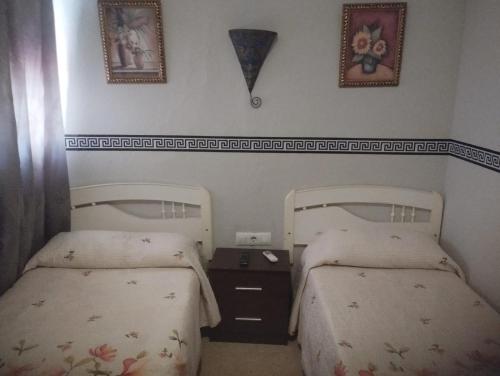 a bedroom with two beds and a nightstand between them at Hospedería Lucano in Córdoba
