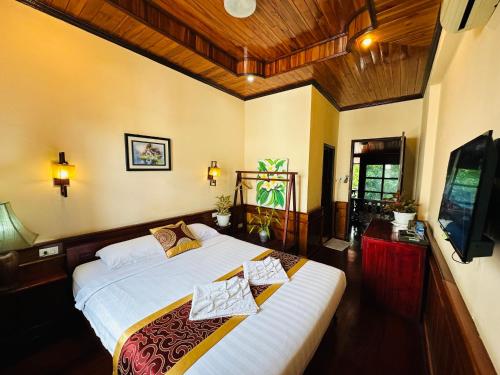 a bedroom with a large bed and a television at Ammata Boutique Villa in Luang Prabang