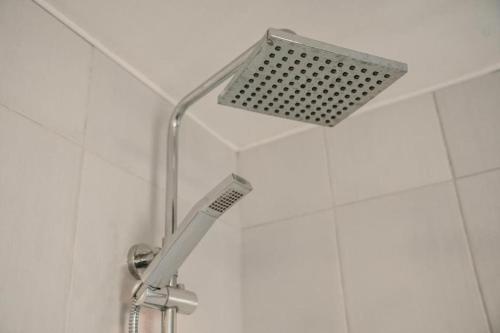 a shower head in a white tiled bathroom at The Georgian Townhouse - 4 Bed House in Whitehaven