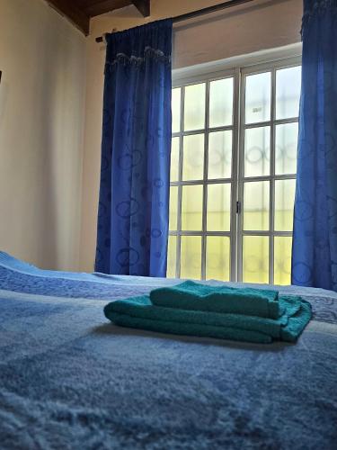 a green towel laying on a bed in front of a window at La joyita in Ituzaingó