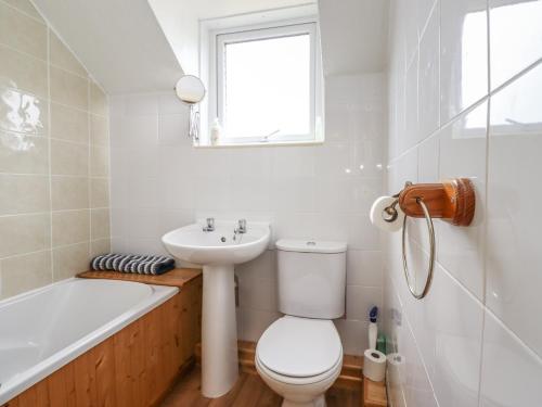 a bathroom with a toilet and a sink and a bath tub at Wayside Cottage in Newton-by-the-Sea