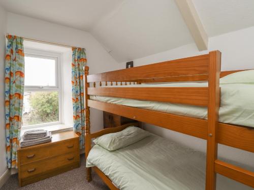 a bedroom with two bunk beds and a window at Wayside Cottage in Newton-by-the-Sea