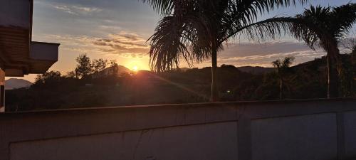 a sunset over a concrete wall with palm trees at Casa com piscina e muita tranquilidade in Rio de Janeiro