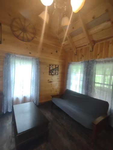 a living room with a couch and two windows at Tranquil Waters Cabin in Frenchburg