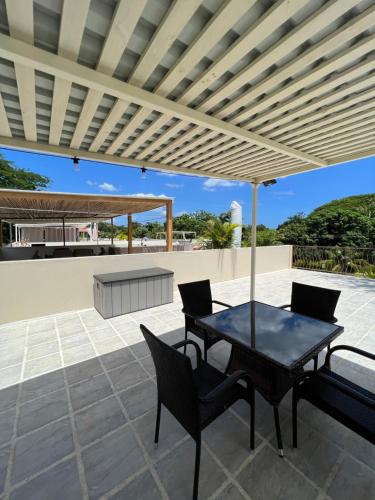 a patio with a table and chairs under a pergola at Charming Condo With A Rooftop, Across Beach in Coco