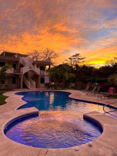 a large swimming pool with a sunset in the background at Charming Condo With A Rooftop, Across Beach in Coco
