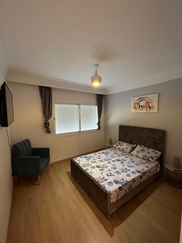 a bedroom with a bed and a chair at Place Mozart - centre-ville in Tangier