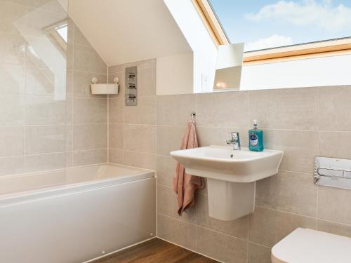 a bathroom with a sink and a toilet and a bath tub at Magnolia Cottage in Appledore