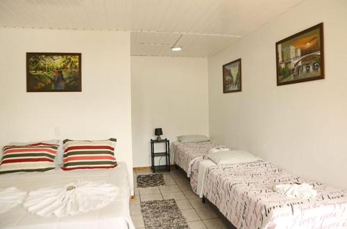 Dos camas en una habitación con paredes blancas. en Pousada Don Raton, en Campos do Jordão