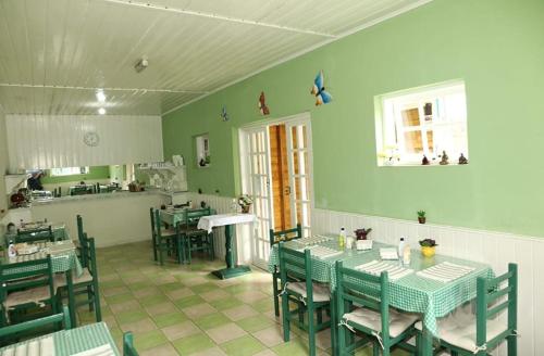 a restaurant with green walls and tables and chairs at Pousada Don Raton in Campos do Jordão
