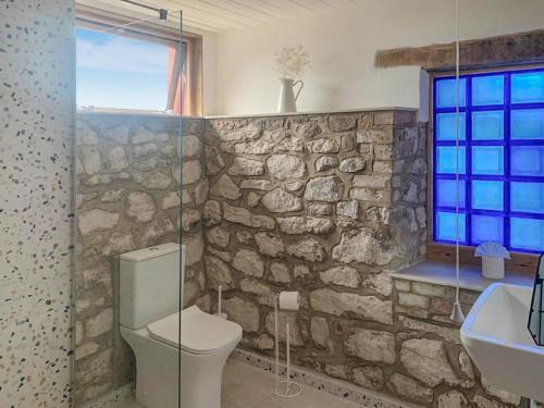 a stone wall bathroom with a toilet and a sink at Ceiliog Bach in Llangennith