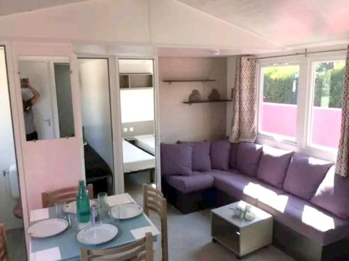 un salon avec un canapé violet et une table dans l'établissement Bungalow charmant près de Vias avec piscine partagée, à Vias