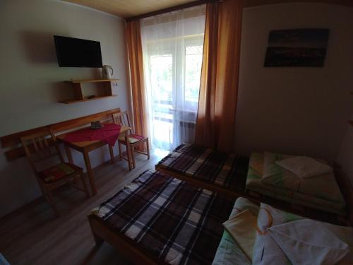 a room with two beds and a table and a window at DG EWA w Polańczyku in Polańczyk