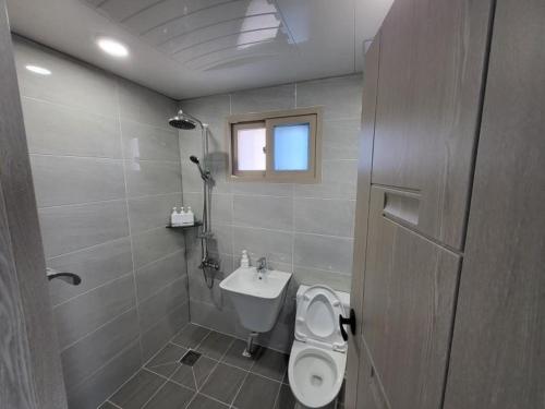 La salle de bains est pourvue de toilettes et d'un lavabo. dans l'établissement Village Pier Pension - Garden, à Yeosu