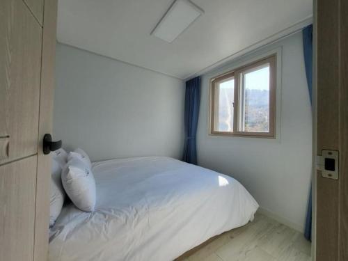 - une chambre avec un lit blanc et une fenêtre dans l'établissement Village Pier Pension - Garden, à Yeosu