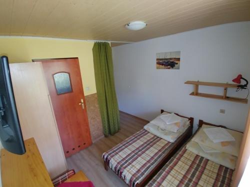 a small room with two beds and a door at DG EWA w Polańczyku in Polańczyk