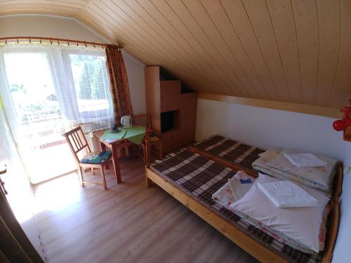 a bedroom with a bed and a table and a window at DG EWA w Polańczyku in Polańczyk