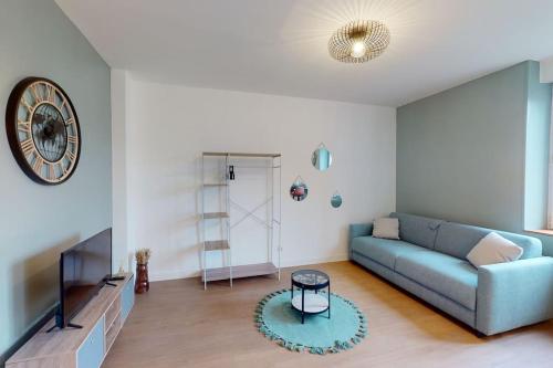 sala de estar con sofá azul y reloj en Un trou de verdure, en Charleville-Mézières