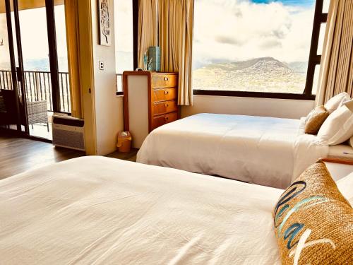 two beds in a room with a view of a mountain at French Banyan in Honolulu