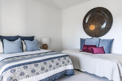 a bedroom with two beds and a fan on the wall at Okiwi Landing in Raglan