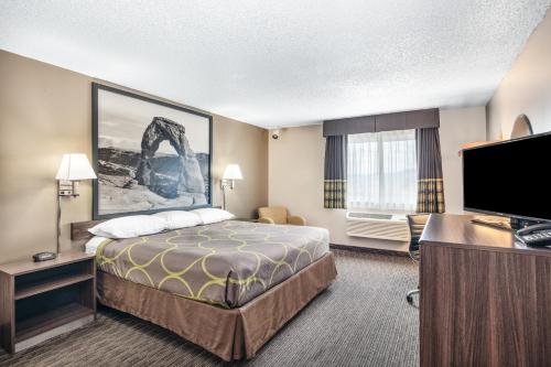 a hotel room with a bed and a flat screen tv at Super 8 by Wyndham Richfield UT in Richfield