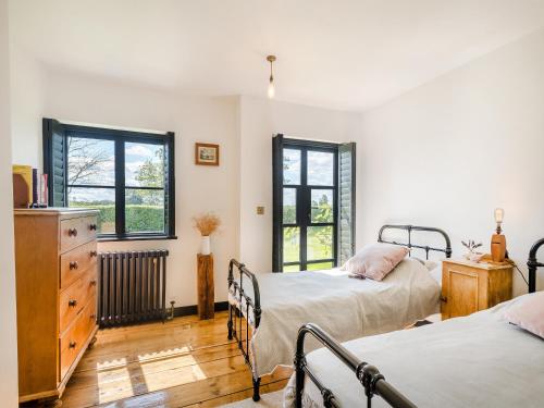 a bedroom with two beds and a dresser and two windows at Little Orchard in Wood Dalling