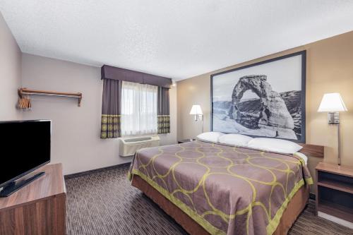 a hotel room with a bed and a flat screen tv at Super 8 by Wyndham Richfield UT in Richfield