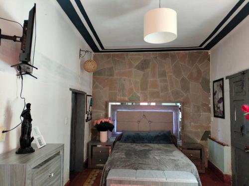 1 dormitorio con 1 cama grande y pared de piedra en Barranca12 en Guanajuato