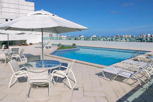 a patio with a table and chairs and a pool at Iguatemi Business & Flat in Salvador