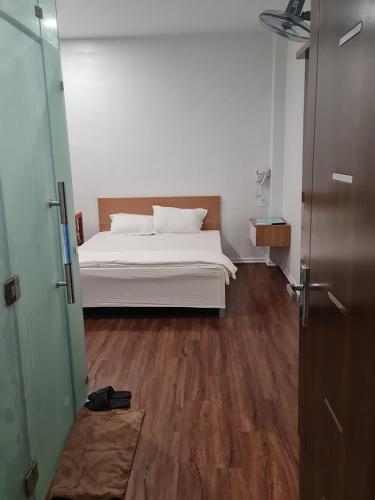 1 dormitorio con cama blanca y suelo de madera en Nhà Nghỉ Đảo Yến 