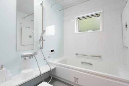 a white bathroom with a tub and a window at Noël HAKONE SENGOKUHARA in Moto-hakone