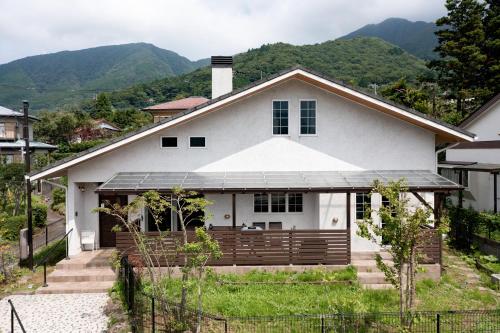 a white house with a deck and mountains in the background at Noël HAKONE SENGOKUHARA in Moto-hakone