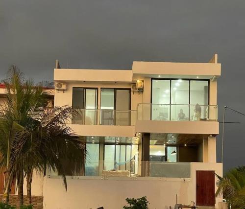 a large house with a balcony and a palm tree at Hermosa casa frentes al mar en Montanita con piscina in Montañita