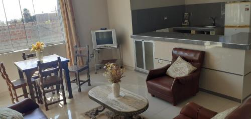 a living room with a couch and a table and a kitchen at Apart Hotel Costa Verde in Tacna