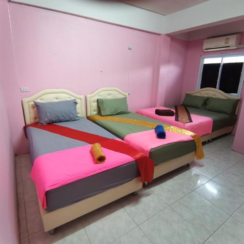 two beds in a room with pink walls at Haadrin Village near the pier in Haad Rin