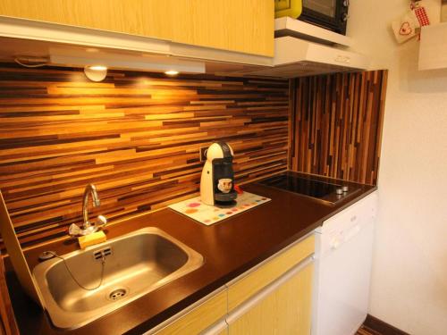 - une cuisine avec un évier et un mur en bois dans l'établissement Luchon - Studio 2/3 pers., balcon, télécabine, proche commerces et thermes - FR-1-313-224, à Luchon
