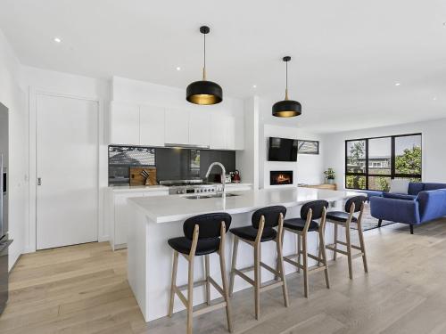 a kitchen with a large white island with bar stools at Pool and Spa - 300m walk to Beach in Mount Martha