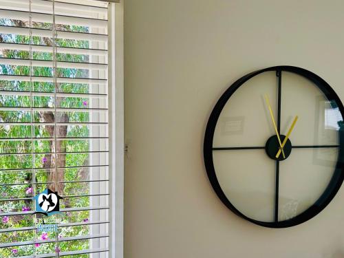 a black and white clock on a wall next to a window at 3BR Updated Coastal Beach House in Funky Port Elliot in Port Elliot