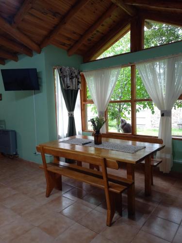 comedor con mesa de madera y ventanas en MAE en Esquel