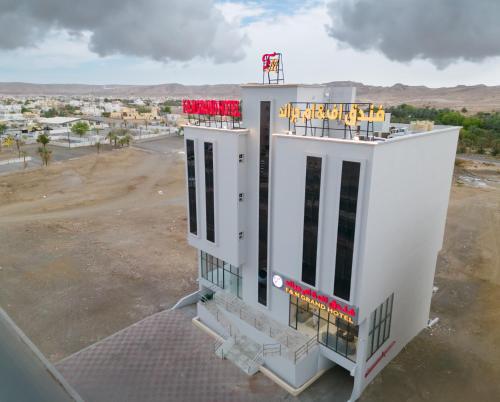 a white building with red and yellow signs on it at F&M Grand Hotel in ‘Ibrī