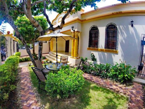 a table with an umbrella in front of a house at Casa Blanca María Barranquilla - Authentic colonial house in Barranquilla
