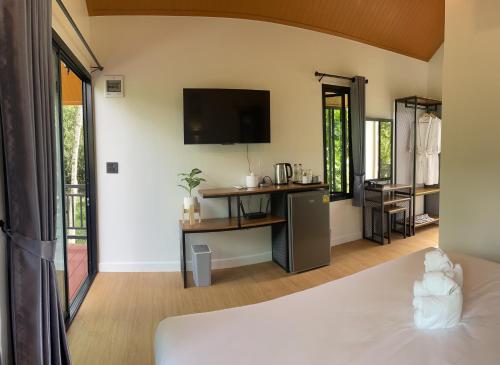 - une chambre avec un lit et une télévision murale dans l'établissement บ้านสวนเรินย่า(เรินย่าคาเฟ่), à Thung Song