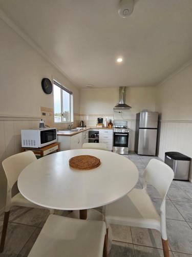 a kitchen with a white table and white chairs at Prom Gate Getaway in Yanakie