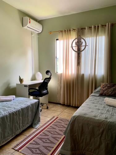 a bedroom with two beds and a desk and a chair at Hostel Portal da Montanha in Blumenau