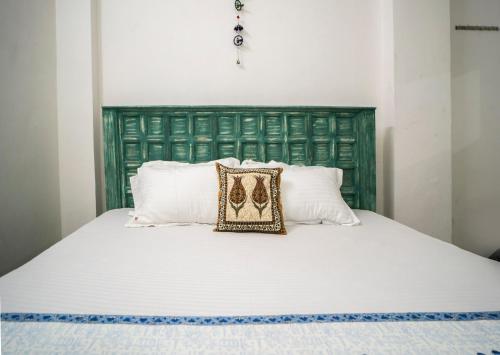 a bed with a green headboard and a pillow on it at Soham Haveli Udaipur in Udaipur