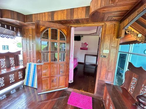 a living room with a wooden door and a bedroom at ปูณิสาวิลล่าPoonisavilla in Ban Khlong Kao (6)