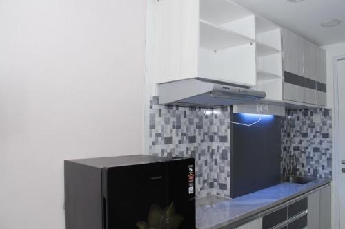 uma cozinha com um frigorífico preto e um micro-ondas em Apartemen Skylounge Makassar em Makassar