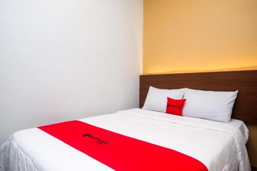 a red and white bed with two red pillows on it at RedDoorz near Tentrem Mall Semarang in Semarang
