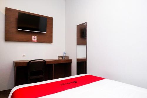 a room with a bed with a desk and a tv at RedDoorz near Tentrem Mall Semarang in Semarang