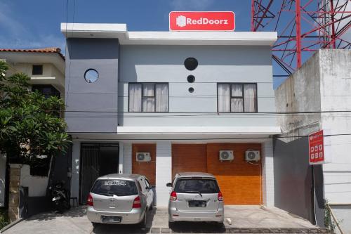 two cars parked in front of a building at RedDoorz near Tentrem Mall Semarang in Semarang